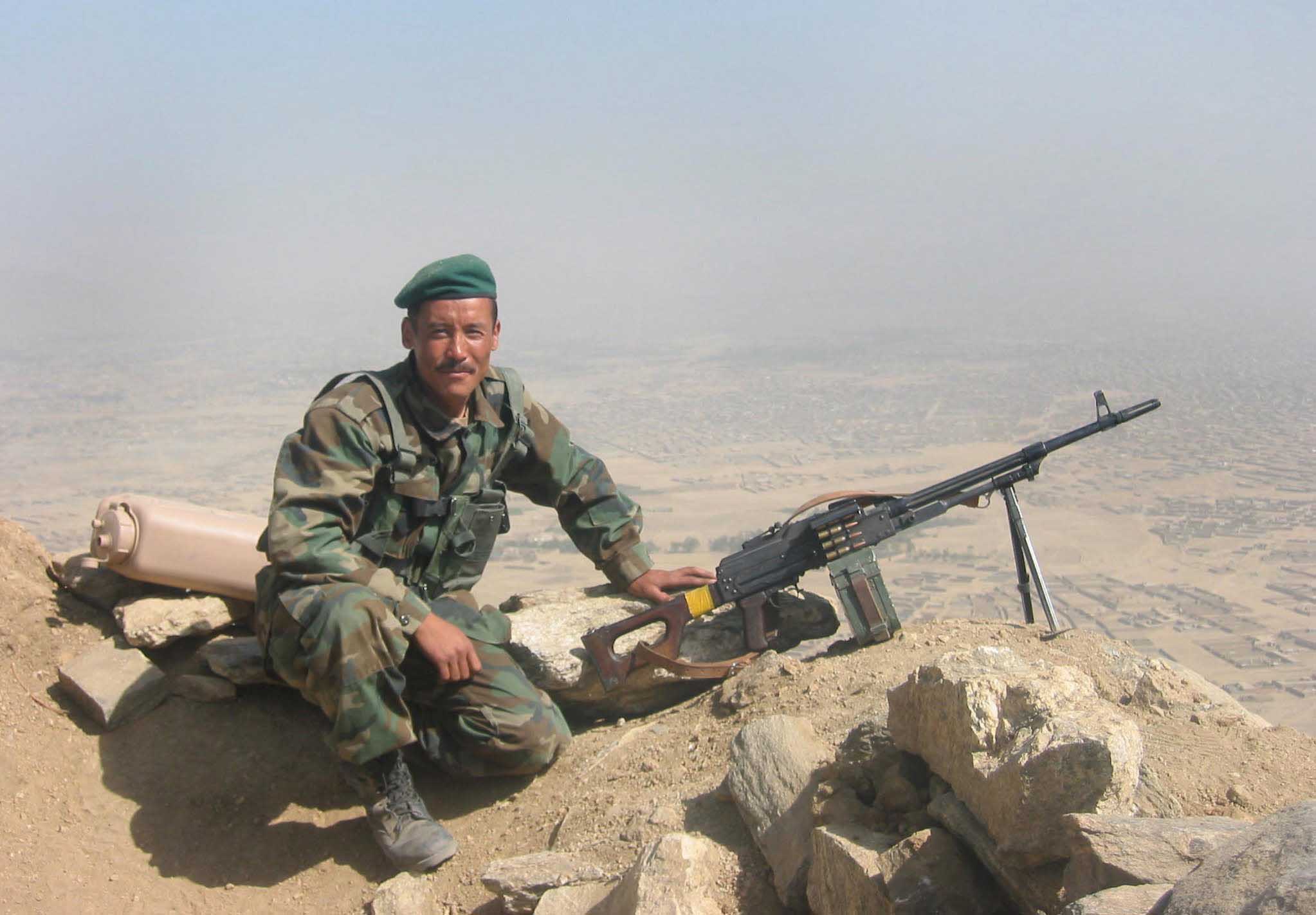 A soldier of the Afghan National Army poses next to his PKM machinegun at a hilltop observation post near Kabul 